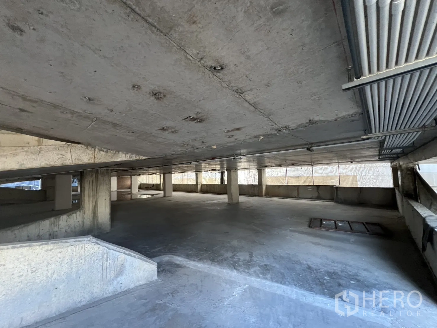 独立商业地产 出售在Watthana, Bangkok - 毛坯停车层，立柱、低矮天花与外露管线。