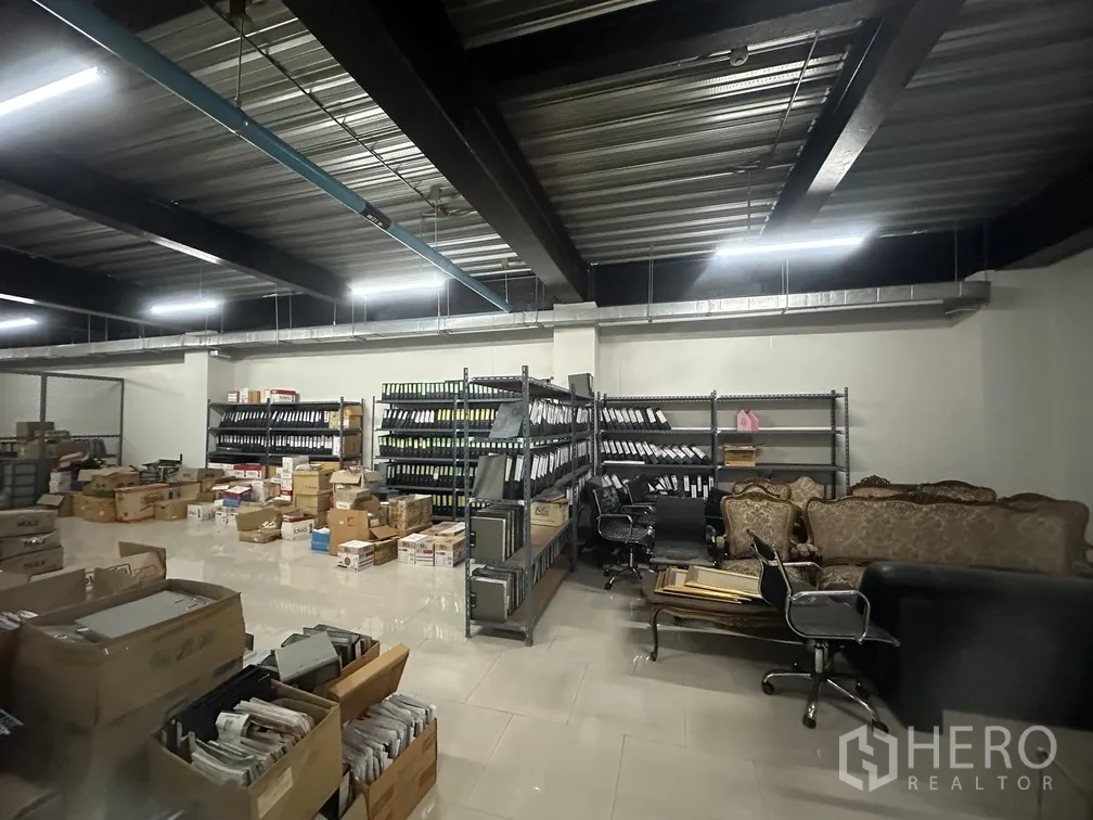 Factory for rent in Lam Luk Ka, Pathum Thani - Wide storage area with racks, cartons and lounge furniture.
