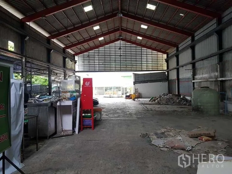 คลังสินค้า ให้เช่าในThung Khru, Bangkok - ทางเดินกลางโกดังมุ่งสู่ประตูใหญ่ มีอุปกรณ์และเศษวัสดุตามแนวผนัง