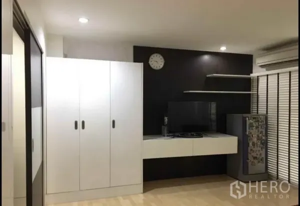 Townhouse for sale in Khlong Toei, Bangkok - Media wall with floating TV console, white wardrobes, shelves and air conditioner.