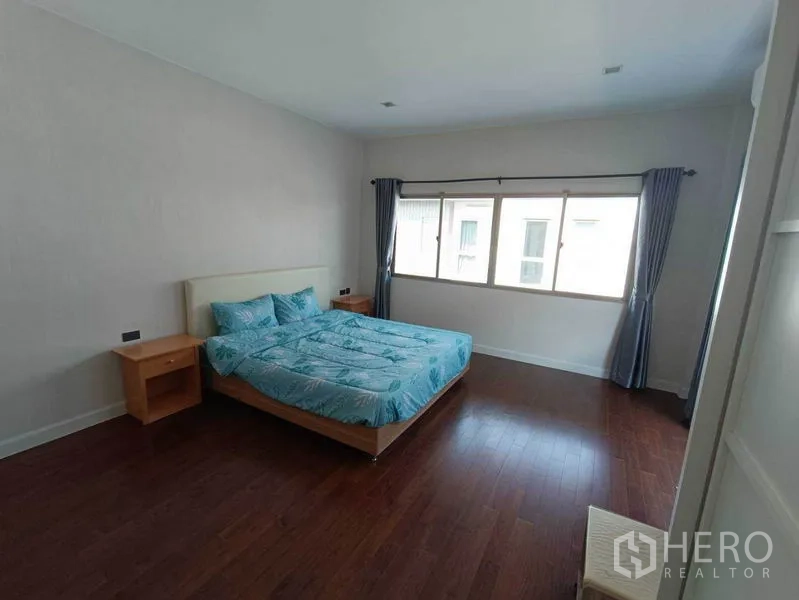 Detached House for rent in Bueng Kum, Bangkok - Spacious master bedroom with wood floors, king bed, and wide windows with curtains.