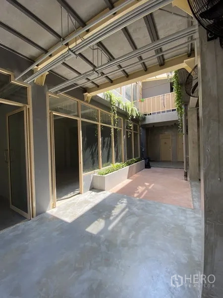 零售空间 出租在Watthana, Bangkok - 带遮棚的庭院走廊，玻璃立面与种植槽的现代商业空间