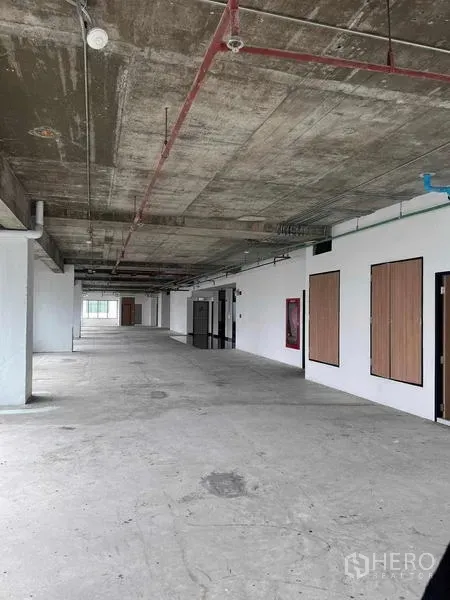 สำนักงาน ให้เช่าในWatthana, Bangkok - โถงทางยาวของชั้นสำนักงาน เพดานเปลือย ผนังสีขาว และประตูห้องบริการหลายจุด