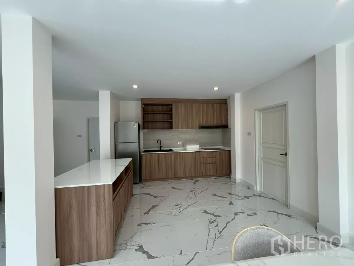 บ้าน ให้เช่าในSuan Luang, Bangkok - ครัวสมัยใหม่ ตู้ลายไม้ เคาน์เตอร์สีขาว และตู้เย็นสเตนเลส.