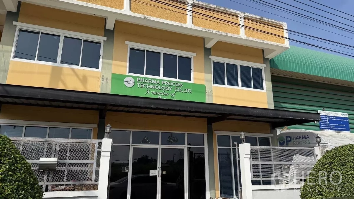 โรงงาน ขายในThanyaburi, Pathum Thani - ด้านหน้าอาคารสำนักงานสองชั้นของโรงงาน หน้าต่างบานใหญ่ ประตูรั้ว พร้อมหลังคาโกดังโค้งสีเขียว
