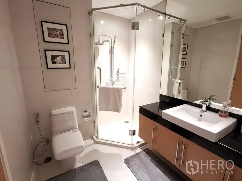 Condominium for rent in Watthana, Bangkok - Guest bathroom with glass shower enclosure, modern vanity, and toilet.