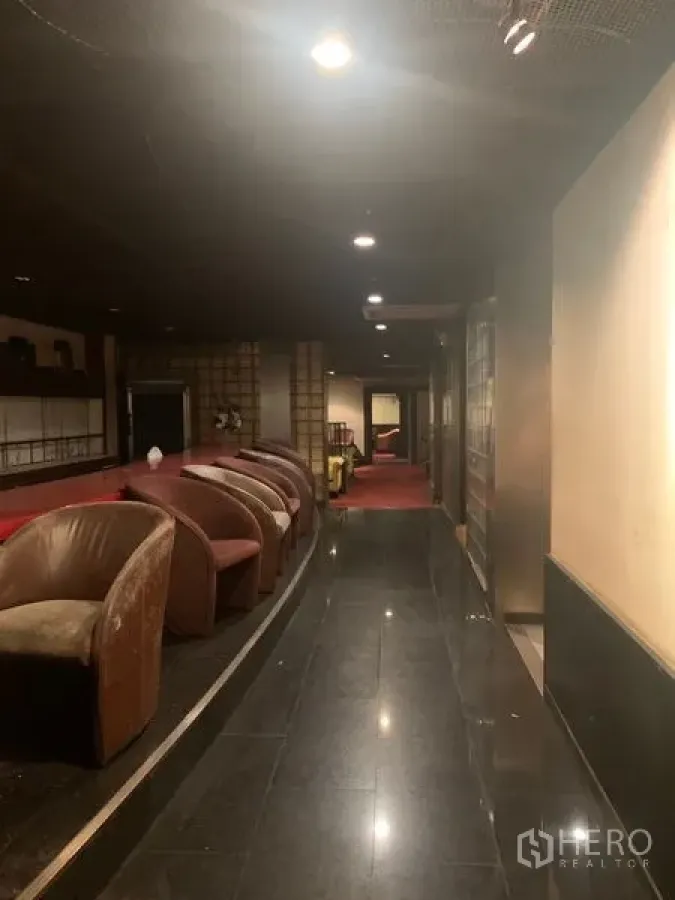 零售空间 出租在Bang Rak, Bangkok - 灯光柔和的走廊，黑色亮面地板与休闲座椅的零售空间。