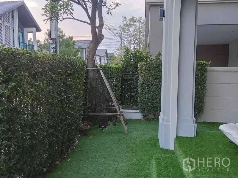 Detached House for rent in Bang Phli, Samut Prakan - Landscaped side yard with hedges, mature tree and green lawn.