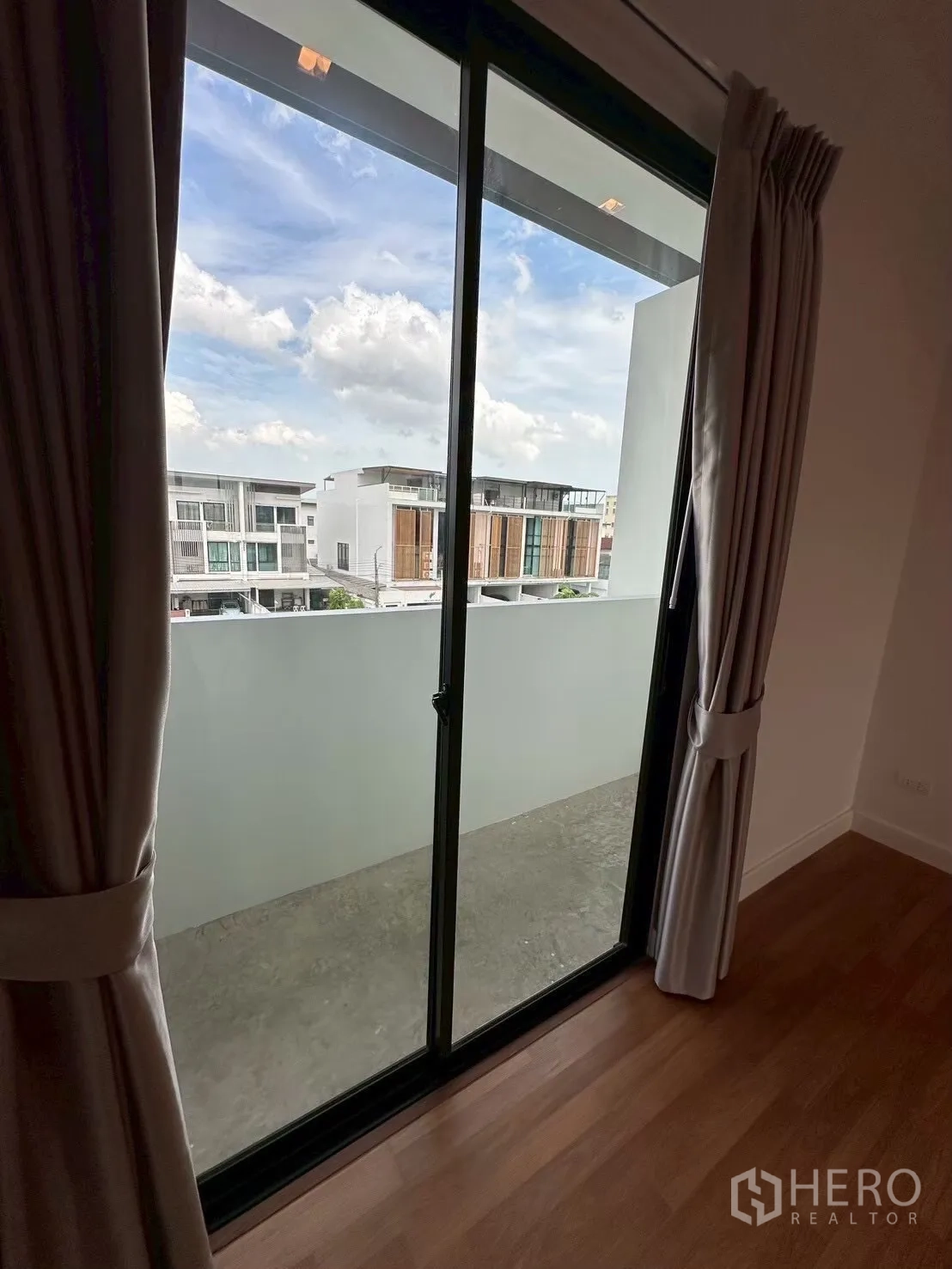 สำนักงานที่บ้าน for rent in Lat Phrao, Bangkok - ประตูกระจกบานเลื่อนจากห้องนอนออกสู่ระเบียงเล็ก พร้อมผ้าม่านและวิวเพื่อนบ้าน.