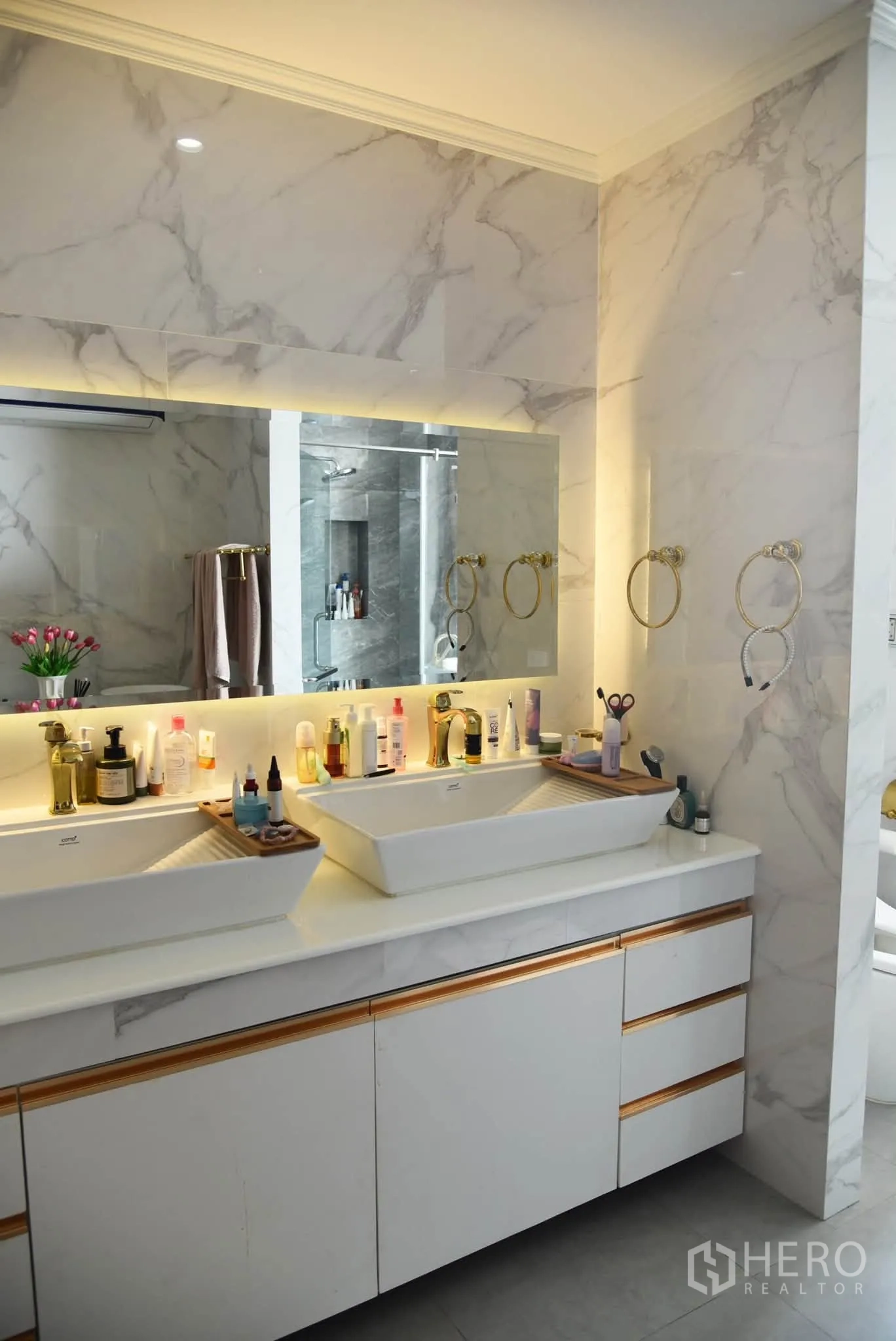 Condominium for sale in Khlong San, Bangkok - Double vanity with a large backlit mirror and marble surfaces in the bathroom.