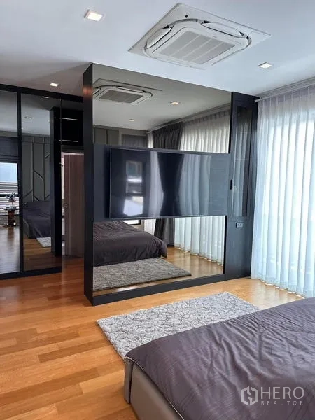独立式住宅 出租在Prawet, Bangkok - 现代卧室，带分隔电视墙、镜面衣柜和木地板。