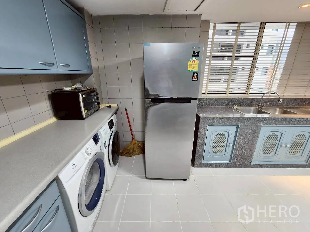 คอนโด ให้เช่าในKhlong Toei, Bangkok - มุมครัวมีตู้เย็น เครื่องซักและอบผ้า ข้างอ่างล้างจานคู่และมู่ลี่