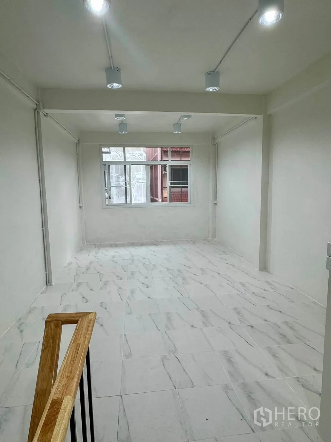 Shophouse for rent in Sathon, Bangkok - Bright upper floor room with marble-look tiles and window lighting.