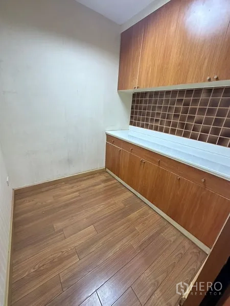Office Space for rent - Compact pantry with upper and lower wooden cabinets, countertop and wood flooring.