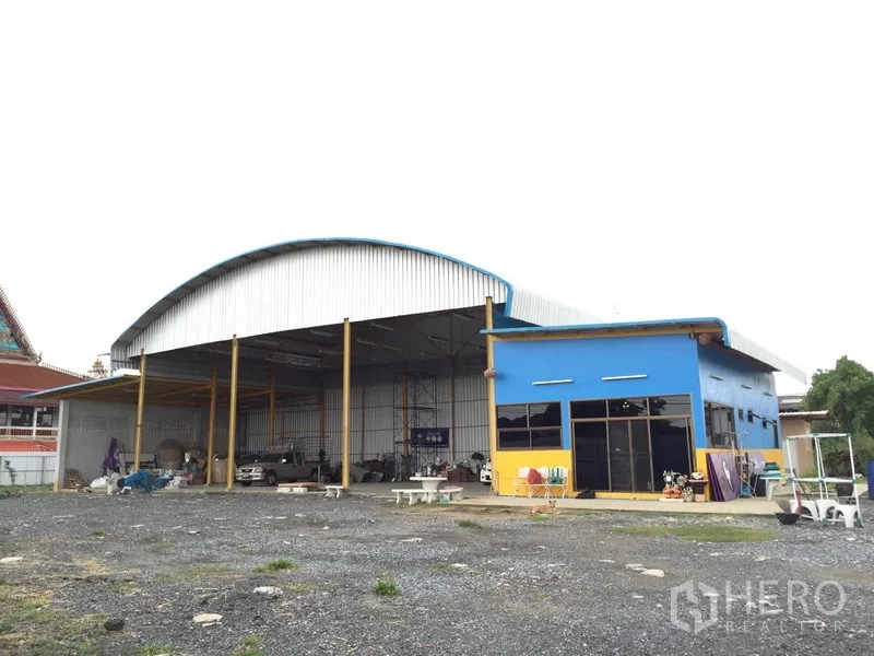 Warehouse for rent in Mueang Pathum Thani, Pathum Thani - Front view of a steel-frame warehouse with a high arched roof and attached glass-front office.