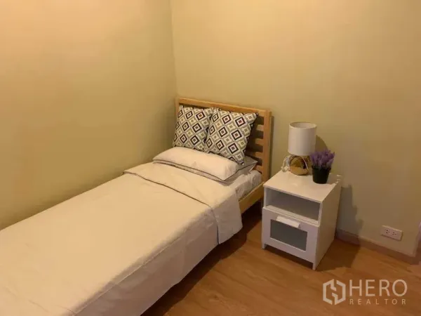 คอนโด ให้เช่าในWatthana, Bangkok - ห้องนอนรอง เตียงเดี่ยว ชุดผ้าปูสีขาว โต๊ะข้างเตียงและโคมไฟ พื้นไม้