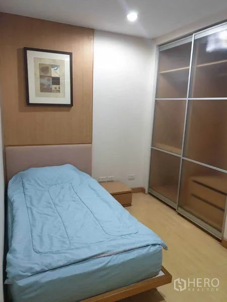 Condominium for rent in Watthana, Bangkok - Second bedroom with single bed, framed artwork, and sliding glass-door wardrobe.