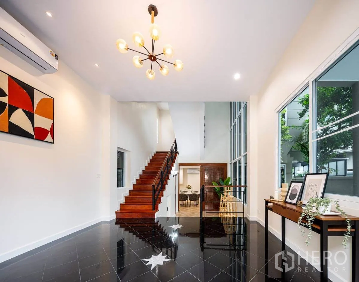 Detached House for rent or sale in Chatuchak, Bangkok - Open foyer showing staircase, statement chandelier, and floor-to-ceiling windows.