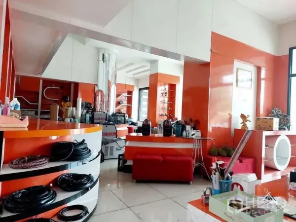 Shophouse for rent or sale in Bang Khun Thian, Bangkok - Bright showroom interior with orange and white counters, built-in shelves, glossy floors and large windows.
