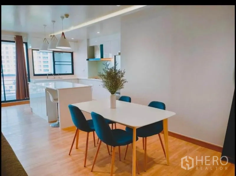 คอนโด ขายในWatthana, Bangkok - พื้นที่รับประทานอาหาร โต๊ะสีขาวและเก้าอี้สีน้ำเงิน ข้างเกาะครัวสว่าง