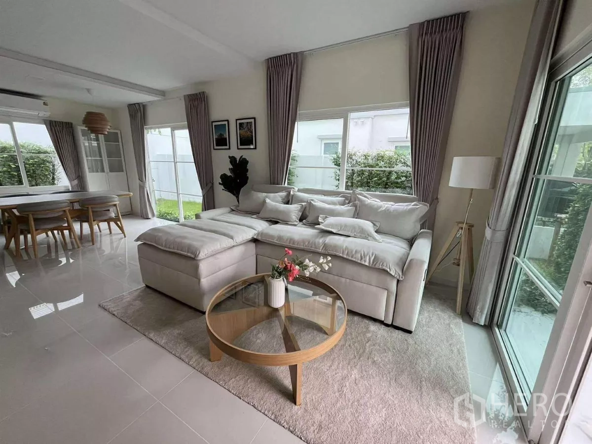 Detached House for rent in Bang Phli, Samut Prakan - Bright living room with L-shaped sofa, round coffee table, and garden views through large windows.