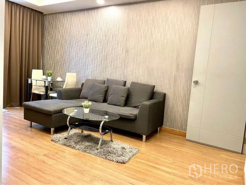 Condominium for rent in Huai Khwang, Bangkok - Cozy lounge area with gray sectional, glass coffee table and dining set.