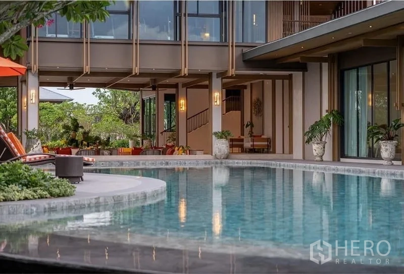 独立式住宅 出租在Bang Kapi, Bangkok - 弧形社区泳池，周围绿植与躺椅