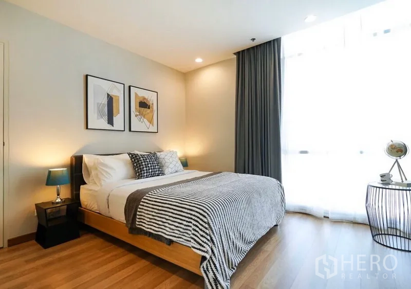 คอนโด ให้เช่าในWatthana, Bangkok - ห้องนอนสว่างพื้นไม้ เตียงควีน งานศิลป์ผนัง และหน้าต่างสูงพร้อมผ้าม่านทึบ