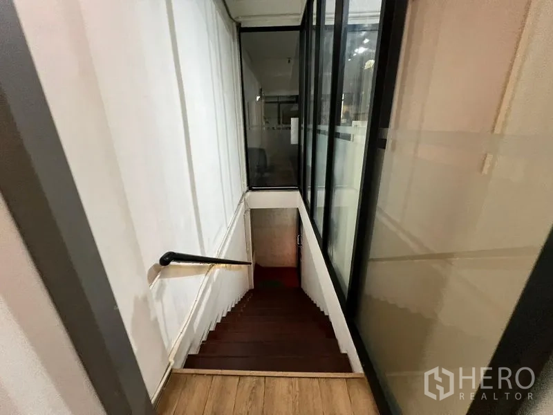 零售空间 出租在Watthana, Bangkok - 楼梯平台走廊，临玻璃墙可望向店内区域。