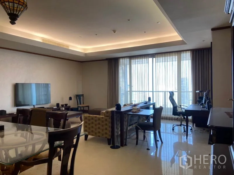 公寓 出租在Sathon, Bangkok - 客厅配电视、沙发与书桌，落地窗及阳台门，天花灯带。