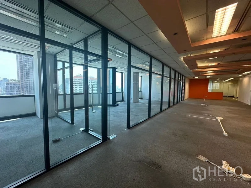 Office Space for rent in Khlong Toei, Bangkok - Glass-walled offices along a hallway with multiple windows and city skyline views.