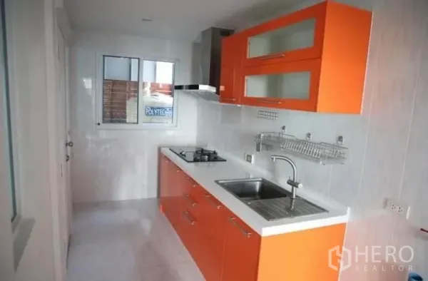 Detached House for rent in Suan Luang, Bangkok - Thai kitchen with sleek orange cabinetry, gas hob, range hood and window.