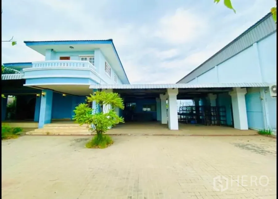 工厂 出租在Sam Phran, Nakhon Pathom - 浅蓝色两层办公楼与仓库外观，前方宽阔硬化场地。