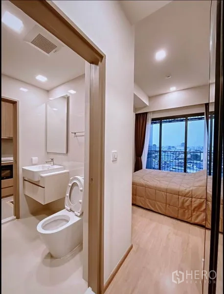 Condominium for sale in Huai Khwang, Bangkok - Passage with bathroom entrance and bedroom opening to floor-to-ceiling windows and balcony.
