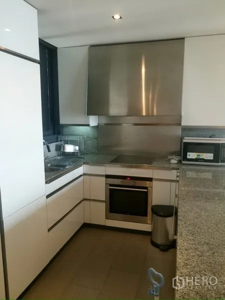 Condominium for rent in Sathon, Bangkok - Modern L-shaped kitchen with stainless backsplash, built-in oven and granite countertop in a Sathon condo.