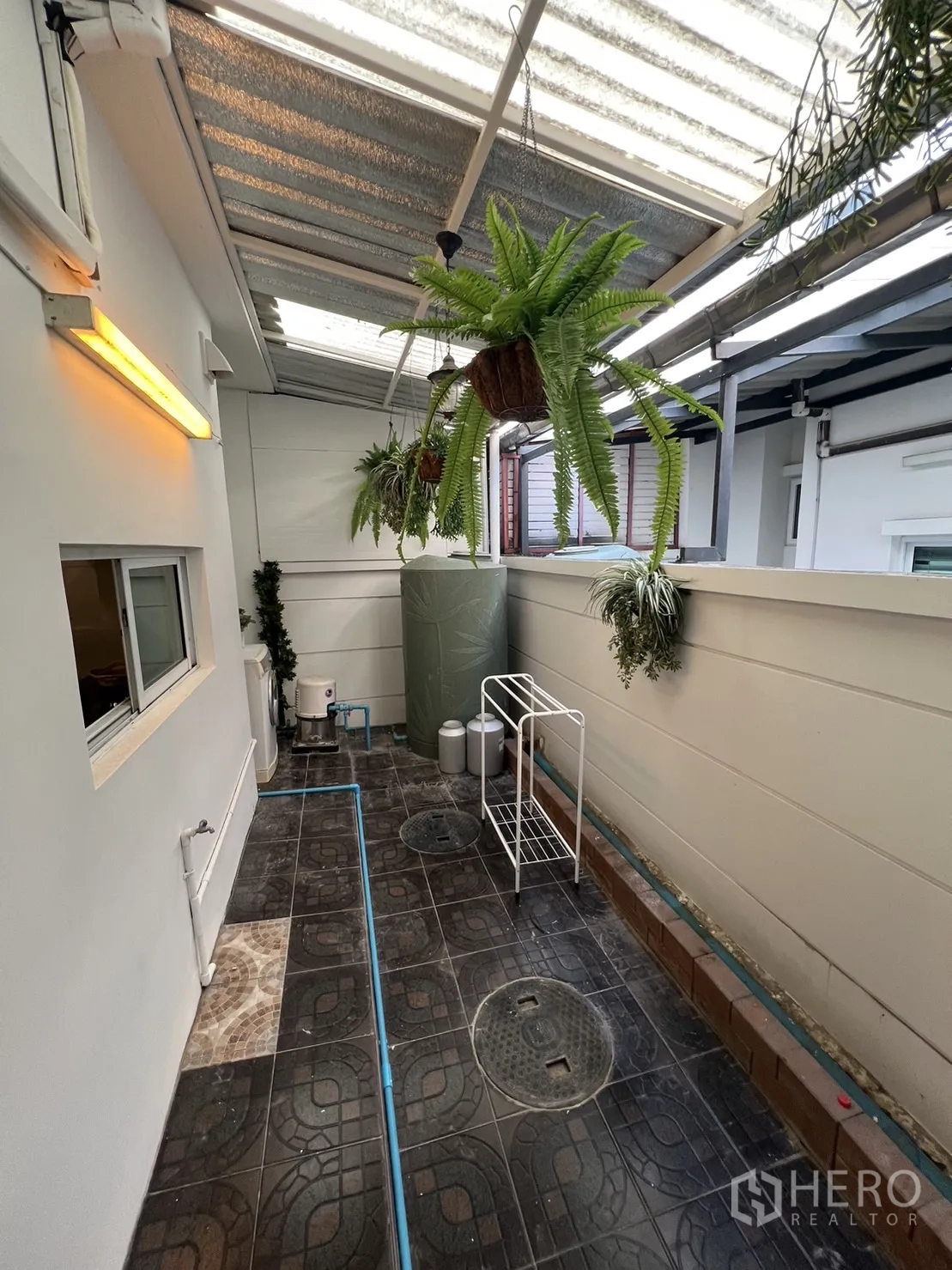 ทาวน์เฮาส์ for rent in Suan Luang, Bangkok - พื้นที่ซักล้างหลังบ้านมุงหลังคาพร้อมต้นไม้แขวนและพื้นกระเบื้อง.