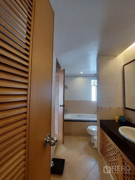 อพาร์ทเมนท์ ให้เช่า - ห้องน้ำโทนอบอุ่นมีอ่างอาบน้ำ โถสุขภัณฑ์ เคาน์เตอร์อ่างล้างหน้า และตู้บานเกล็ดไม้