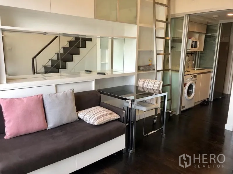 公寓 出租在Khlong Toei, Bangkok - 开放式客厅，沙发与餐桌，旁接厨房与置物架。