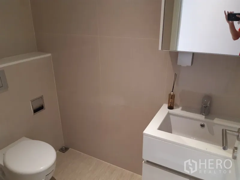 คอนโด ให้เช่าในWatthana, Bangkok - ห้องน้ำที่สองมีเคาน์เตอร์อ่างล้างหน้า ตู้กระจก และโถสุขภัณฑ์โทนสีเรียบ