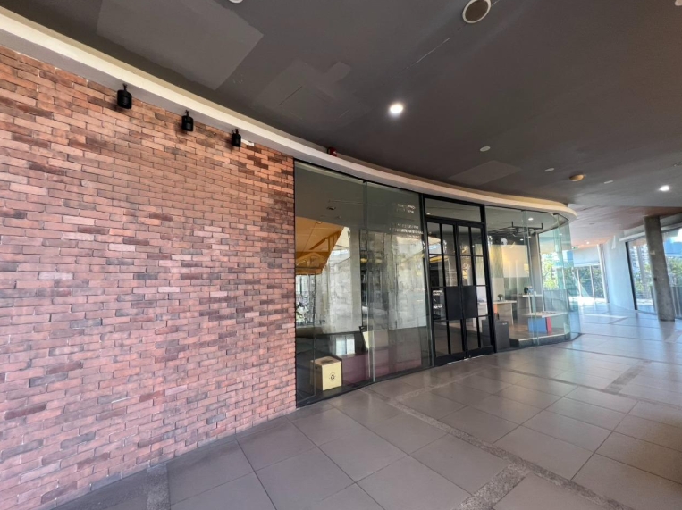 Retail Space for rent in Khlong Toei, Bangkok - Shop entrance showing a brick feature wall and full-height glass doors in a bright Phrom Phong walkway.