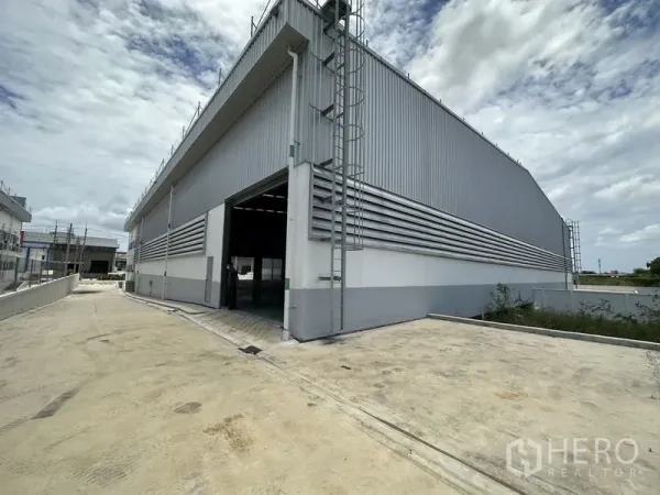 工厂 出租在Mueang Samut Prakan, Samut Prakan - 仓库侧立面，环形车道、开启的卷门与屋顶安全梯。