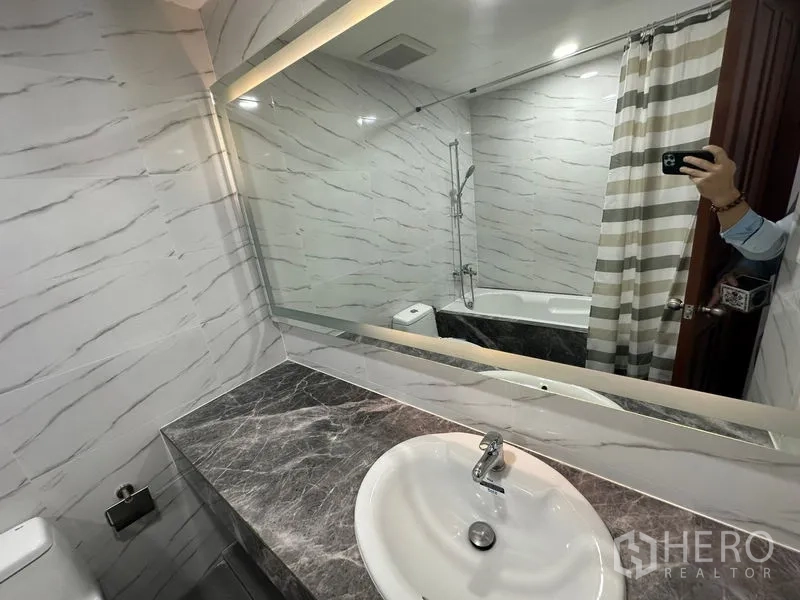 คอนโด ให้เช่าในWatthana, Bangkok - มุมมองห้องน้ำ มีอ่างล้างหน้าเคาน์เตอร์หินอ่อน ผ้าม่านอาบน้ำลายทาง และกระจกเต็มผนัง