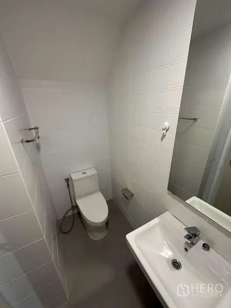 独立式住宅 出租在Prawet, Bangkok - 一层化妆间，坐便器、洗手盆与墙面镜。