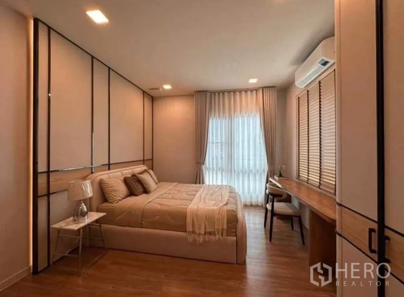 Detached House for rent in Samut Prakan - Cozy bedroom with upholstered bed, feature wall panels, and long built-in desk.