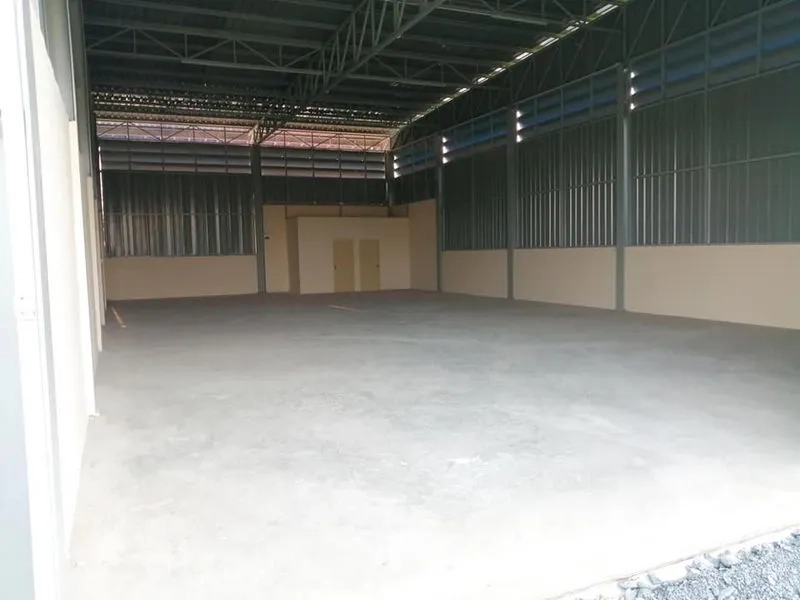 Warehouse for rent in Phra Samut Chedi, Samut Prakan - Spacious warehouse interior with high steel truss roof, concrete floor, and rear utility rooms.