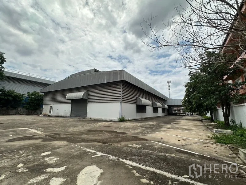 Showroom for rent or sale in Lam Luk Ka, Pathum Thani - Rear warehouse exterior with roller shutters and loading area.