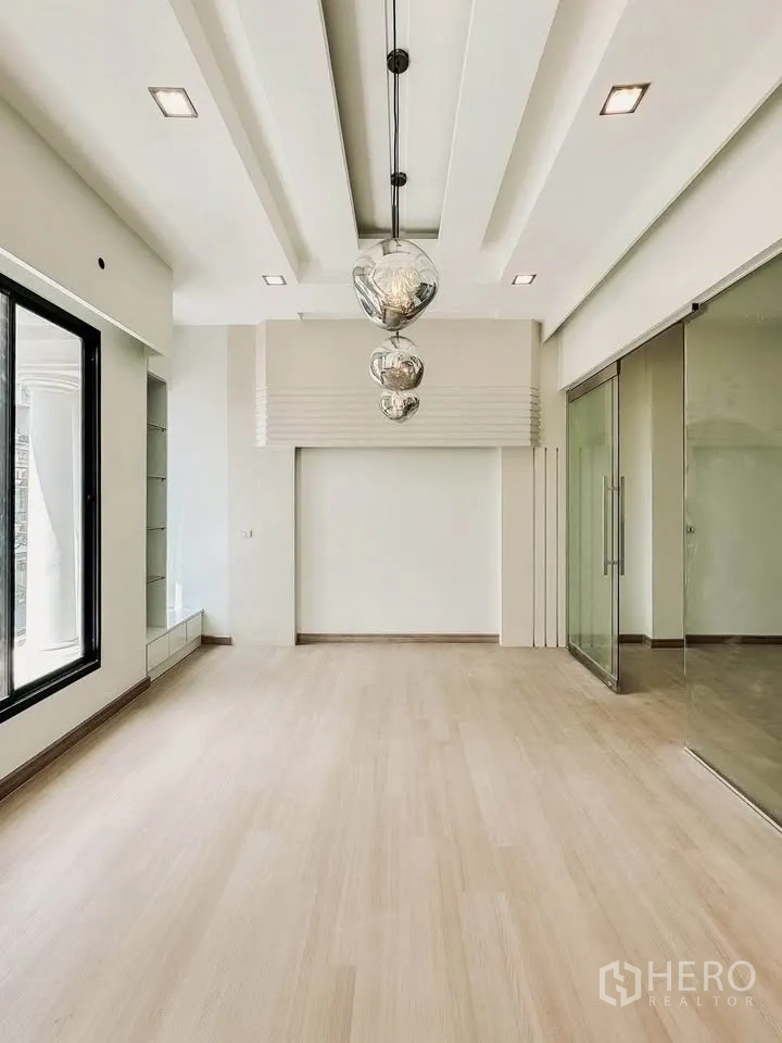 联排别墅 for sale in Wang Thonglang, Bangkok - 明亮客厅，浅木地板、层次吊顶与玻璃隔断。