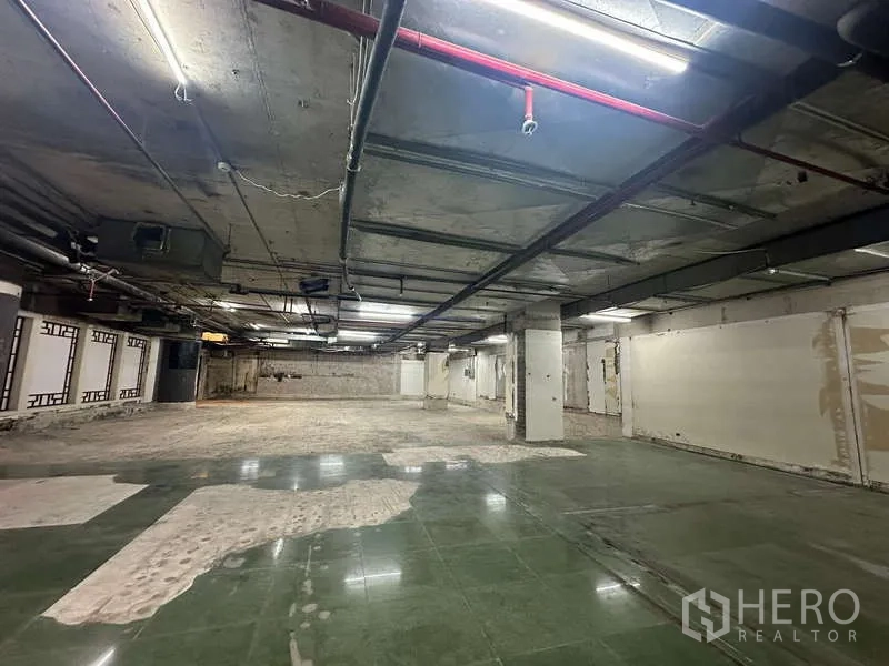 零售空间 出租 - 开放式商铺，中央立柱，绿砖与水泥地混合，带消防喷淋管。