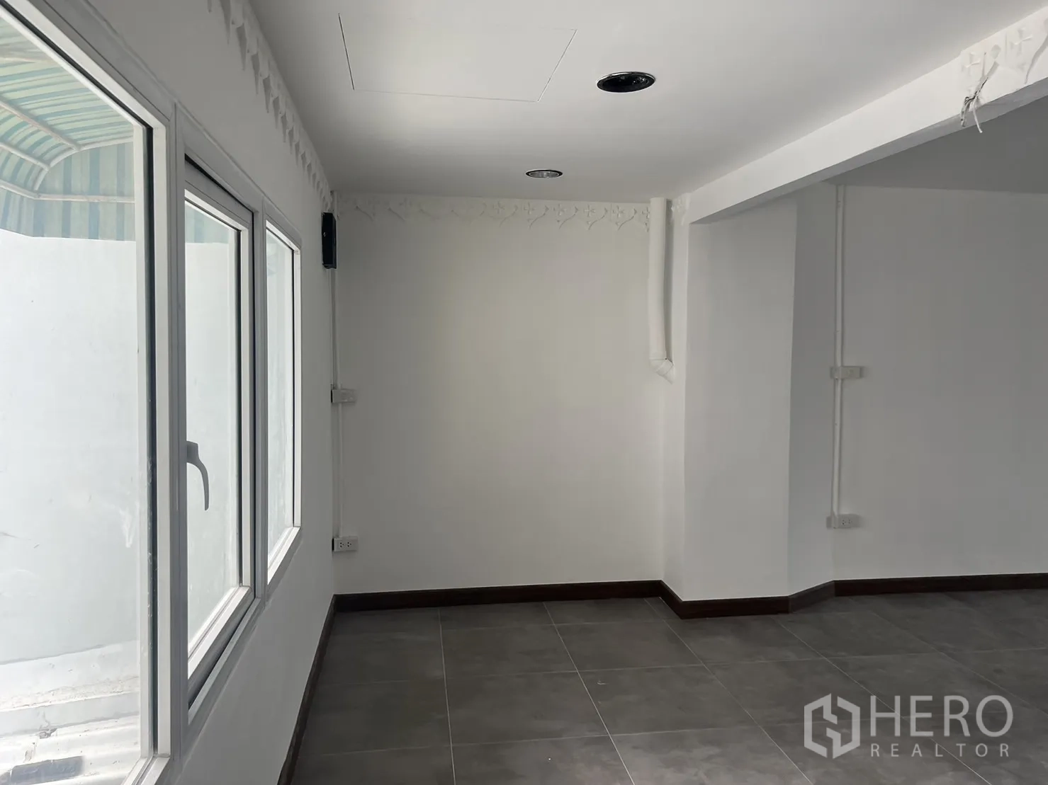 零售空间 出租在Khlong Toei, Bangkok - 明亮内角，白墙、大窗与灰色地砖。