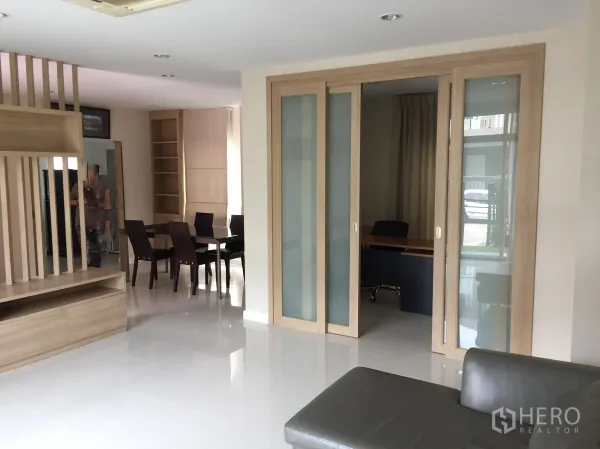 Detached House for rent in Pathum Thani - Bright living area with sliding glass partitions, built-in shelving and an adjacent dining space.